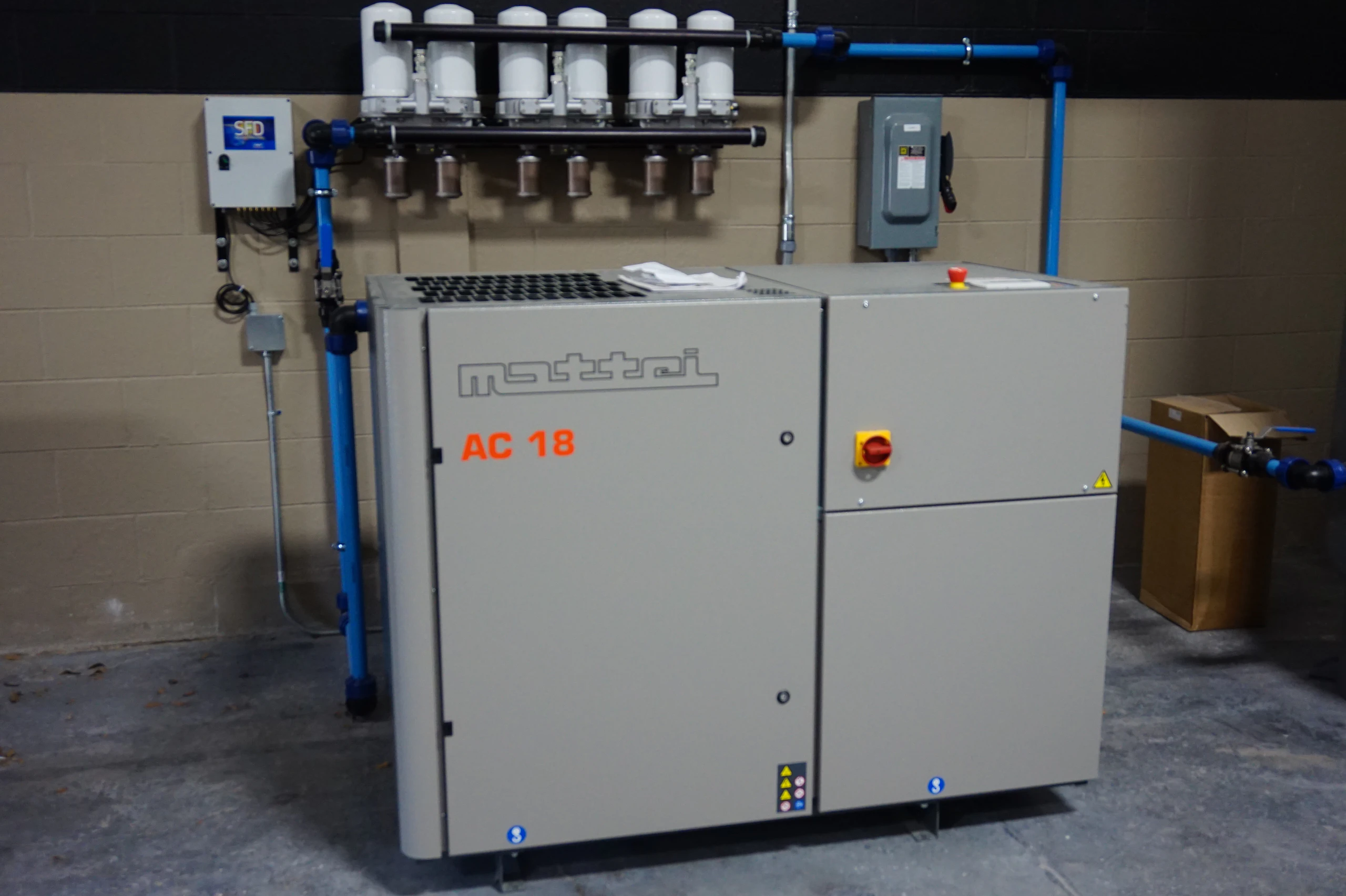 Mattei AC 18 industrial air compressor with connected blue piping in a workshop