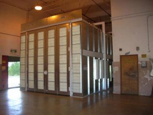 Industrial paint booth with metal frame and filter panels in a warehouse setting