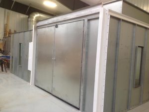 Industrial metal paint booth with large double doors and ventilation system