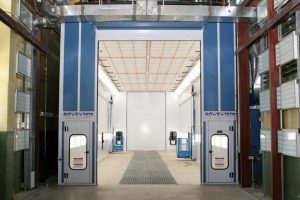 Large industrial paint booth with blue exterior and bright white interior lights