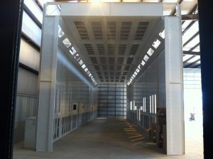 Large industrial paint booth with ventilation panels inside a warehouse