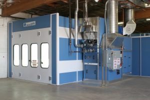 Industrial blue and white paint booth with ventilation system and large front doors