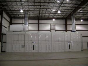 Industrial white spray paint booth with ventilation ducts in warehouse