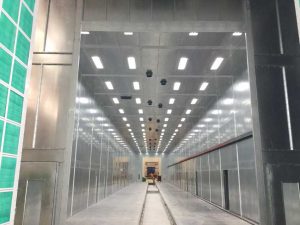 Industrial stainless steel paint booth with overhead lighting and ventilation