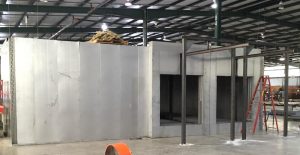 Large metal industrial paint booth under construction in warehouse