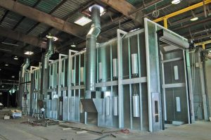 Large industrial paint booth with metal structure and ventilation ducts in factory setting